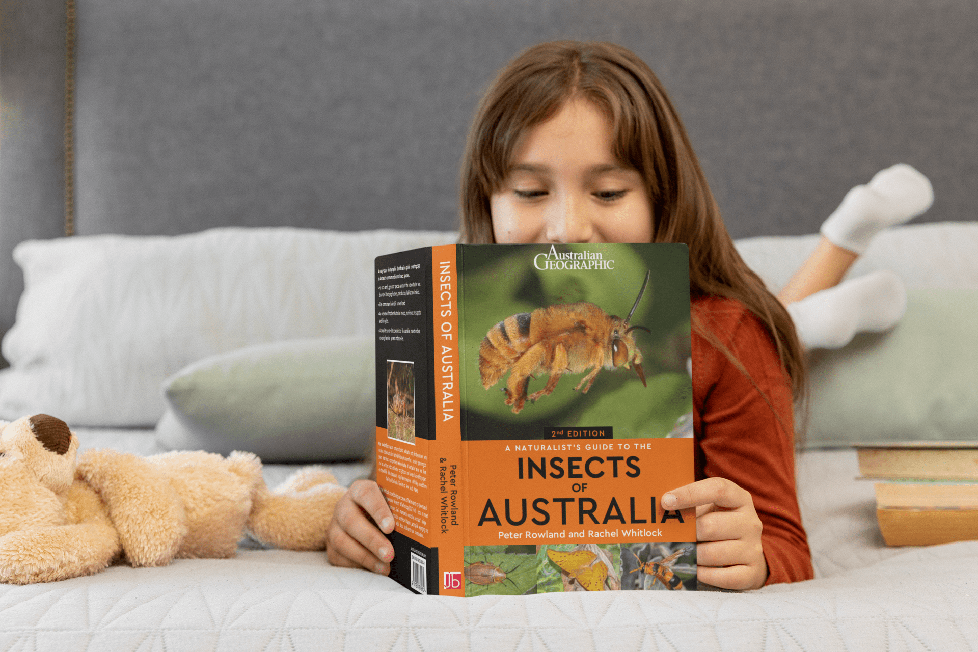 book-mockup-of-a-girl-reading-a copy of the book "A Naturalist's Guide to the Insects of Australia (2nd Edition)"-in-her-bedroom